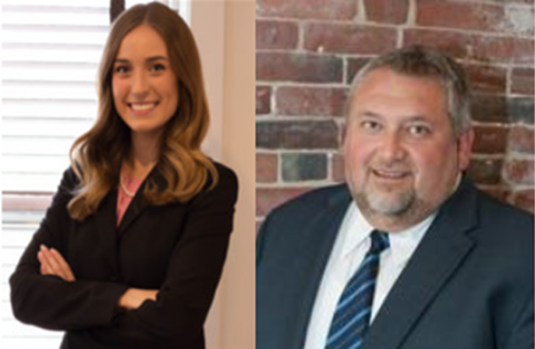 Two professional attorneys in business attire posing for a portrait in a modern office setting.